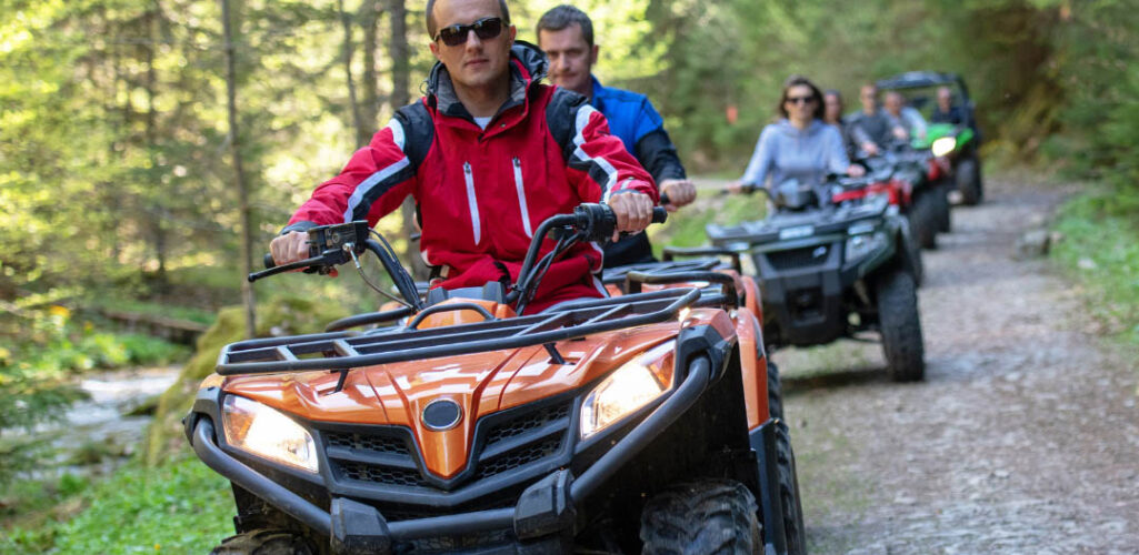 A group of people riding all-terrain vehicles on a forest trail - https://www.stoneinsurancegrp.com/